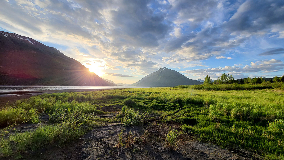 grass and a large pond with mountains in the distance