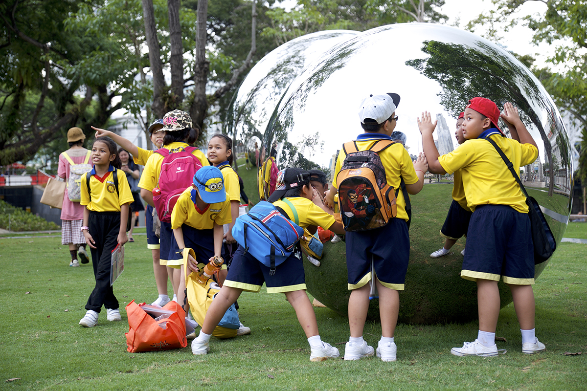 children in yellow tops playing with a big silver ball