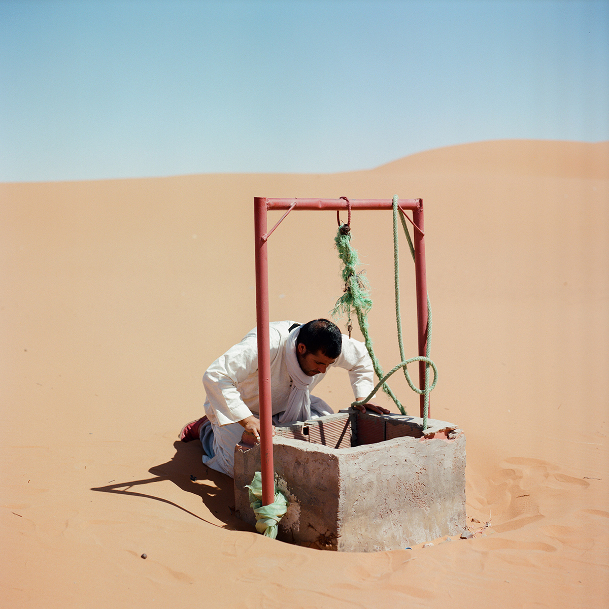 A man looking for water in a well in th desert