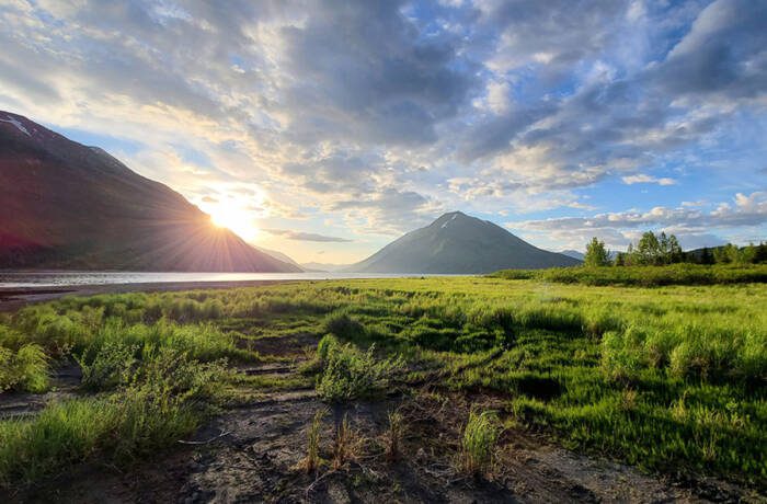 grass and a large pond with mountains in the distance