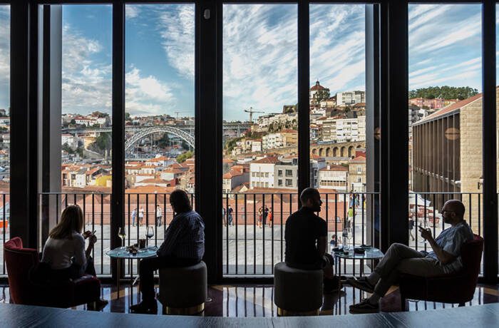 People sitting at tables in front of a large window overlooking a city