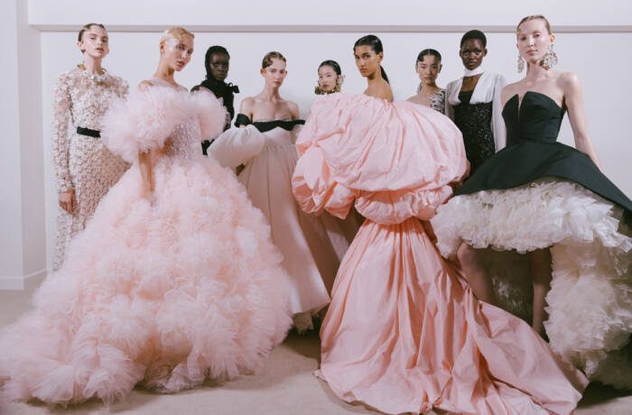 Women standing together wearing big pink and black puffy dresses with petty coats