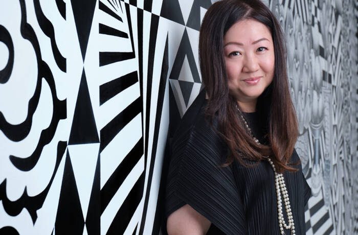 A woman wearing a black top standing next to a white and black wall