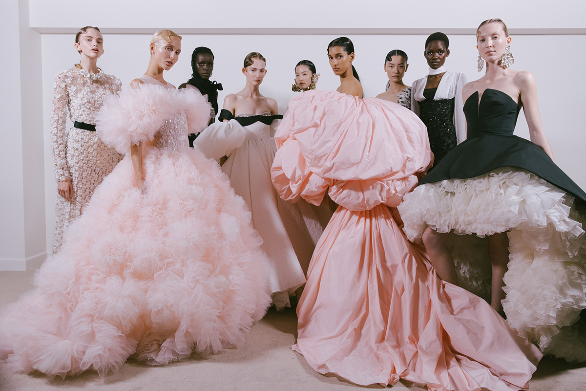 Women standing together wearing big pink and black puffy dresses with petty coats