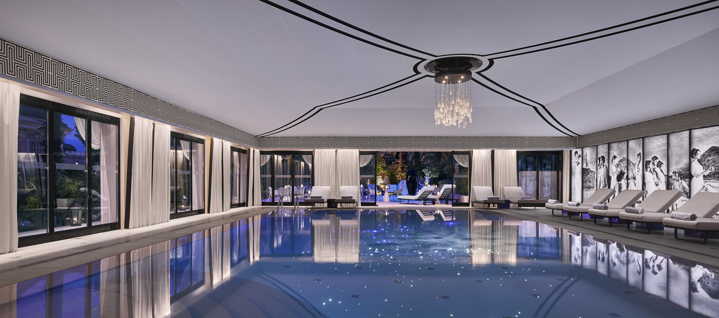 A blue indoor pool with lights at night