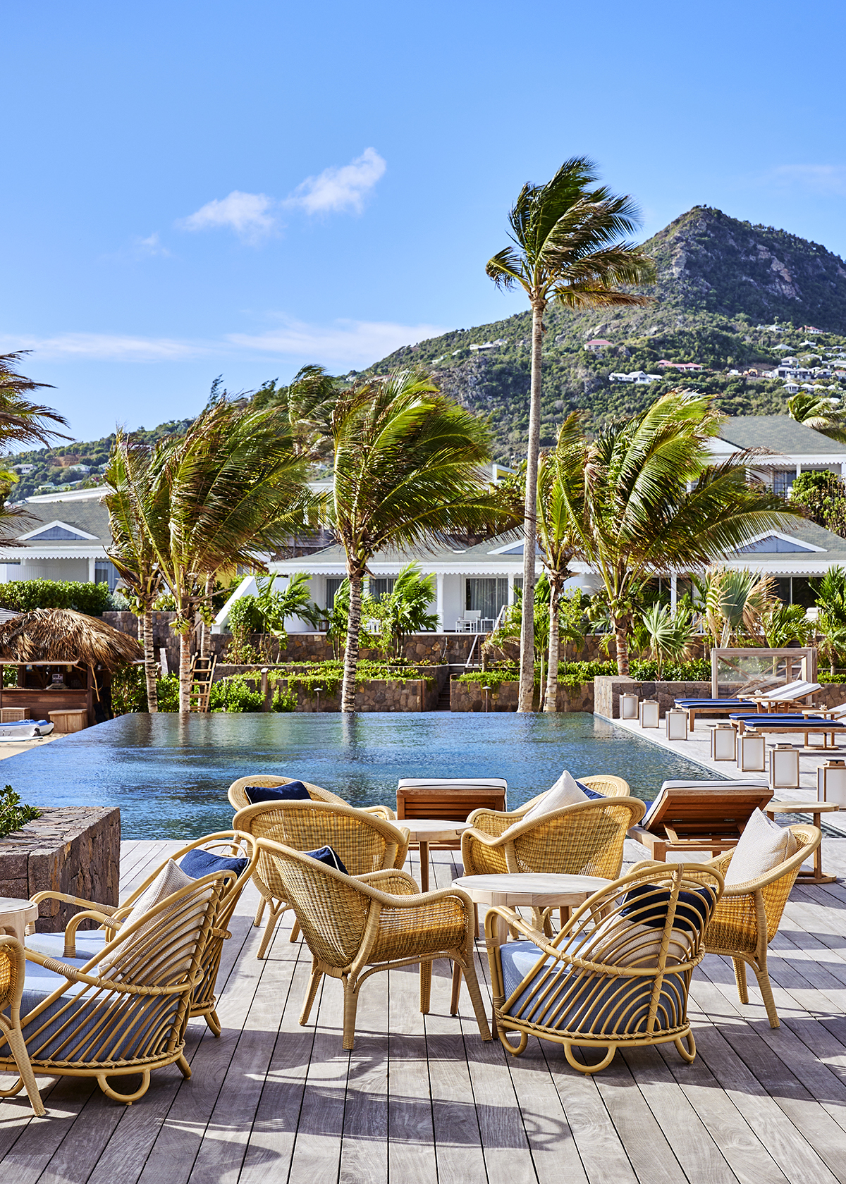 A pool with straw chairs and palm trees around it