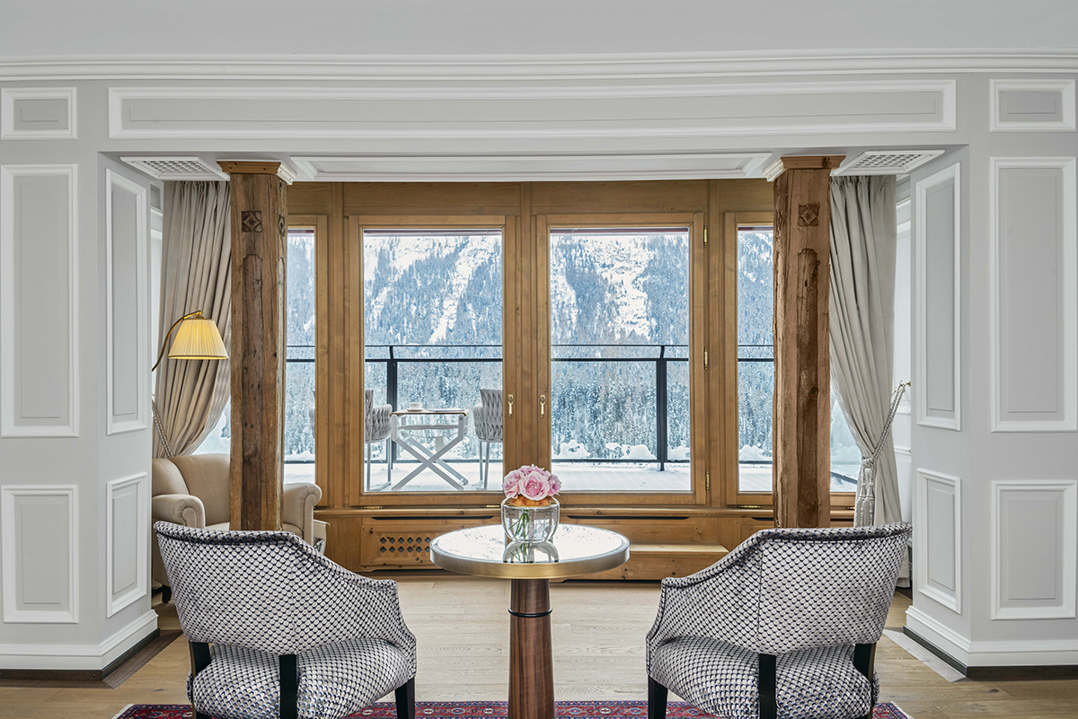 Two grey chairs and a table facing a window overlooking mountains and trees