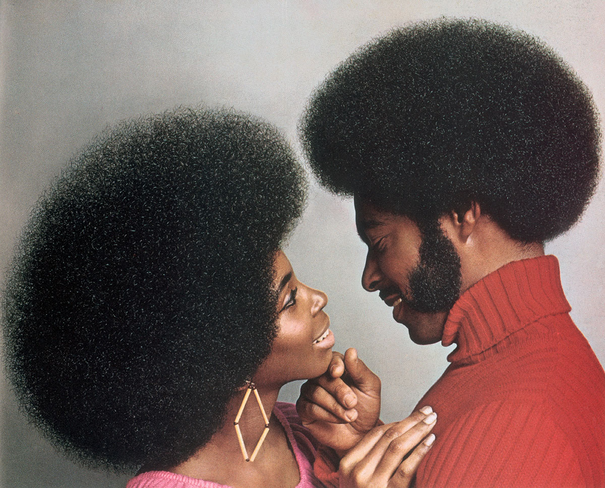 A man and woman with black afros about to kiss
