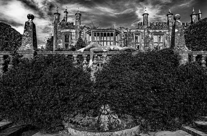 A black and white picture of a house and a woman lying on a balcony