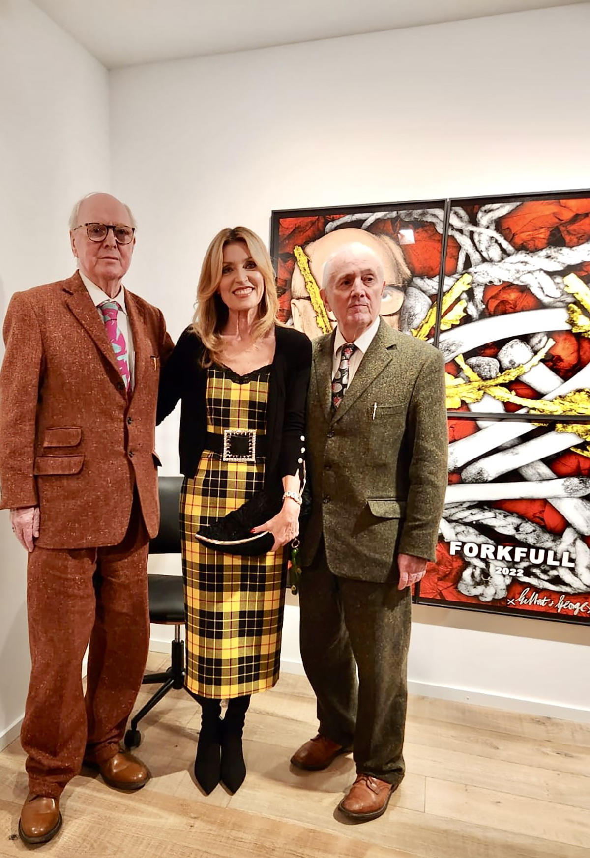 A woman wearing a black and yellow dress standing between two old men