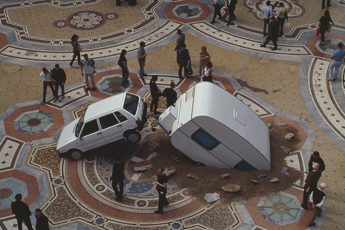 Two cars crashed into a mosaic ground with people standing around it
