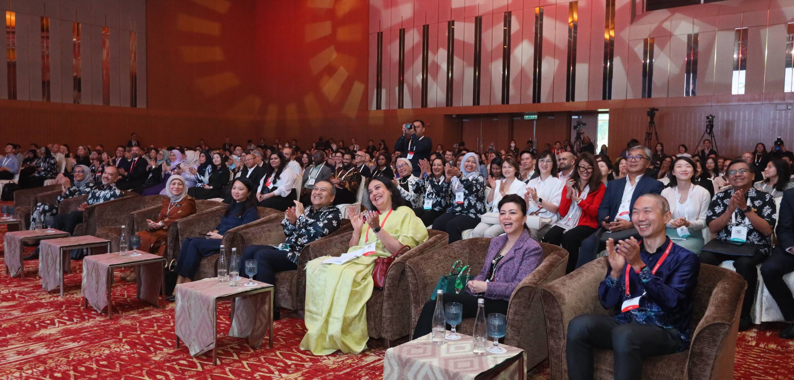 people sitting on chairs in a red room listening to a talk