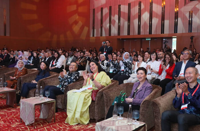 Group of people in a red room watching talk sitting on chairs