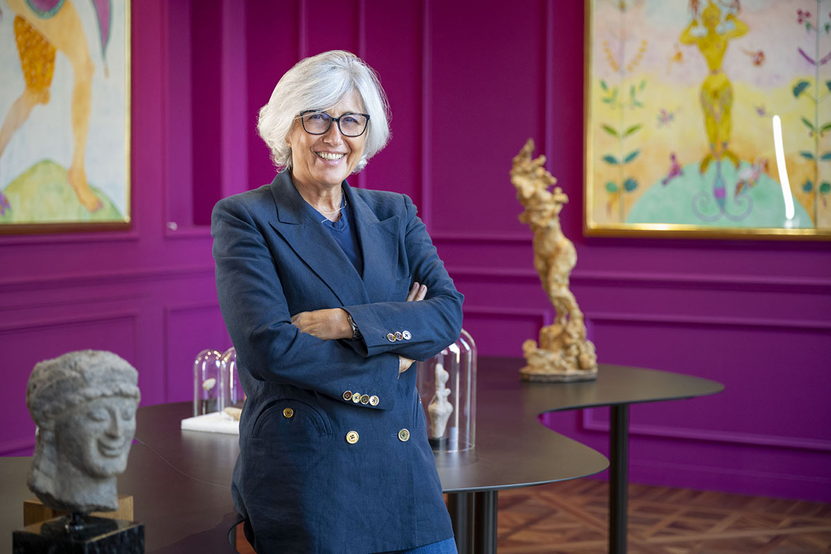 Woman with white hair and glasses crossing her arms and smiling