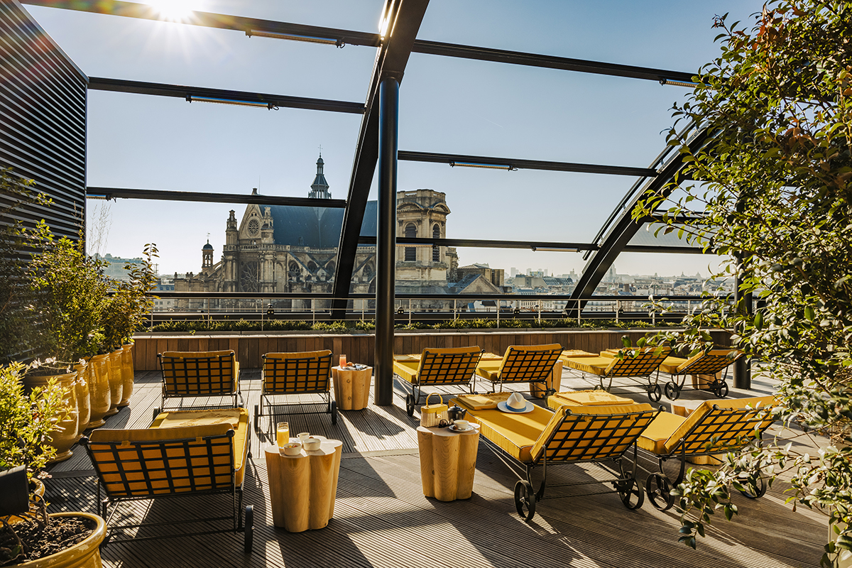 An outdoor terrace with yellow cushioned deck chairs and tables