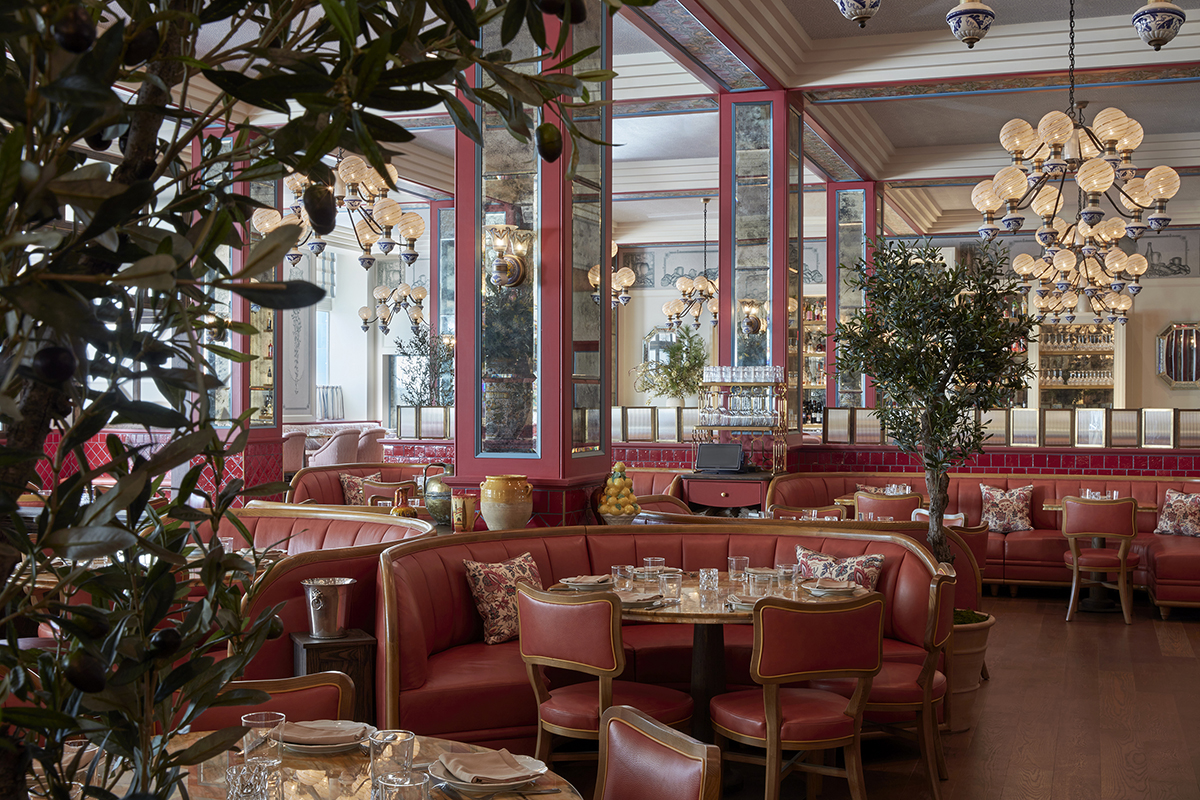 A room with green plants and red leather furniture and mirrored walls