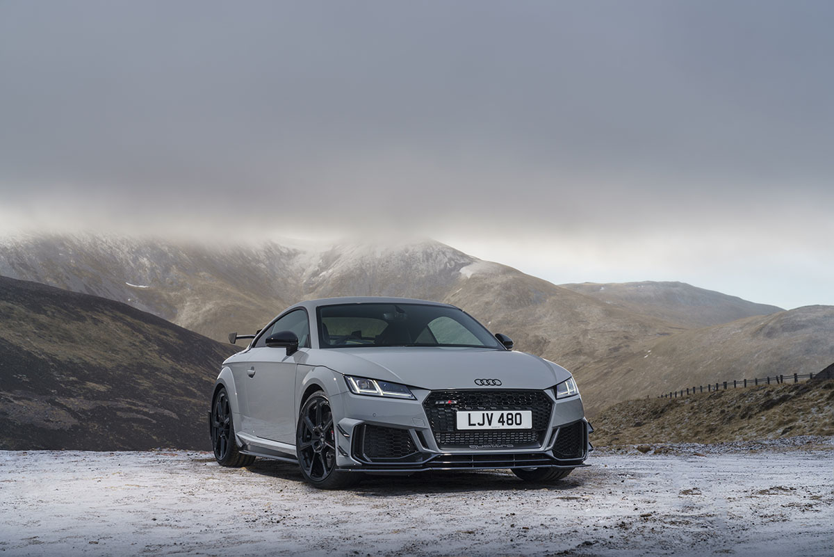 A grey car in the mountains with snow