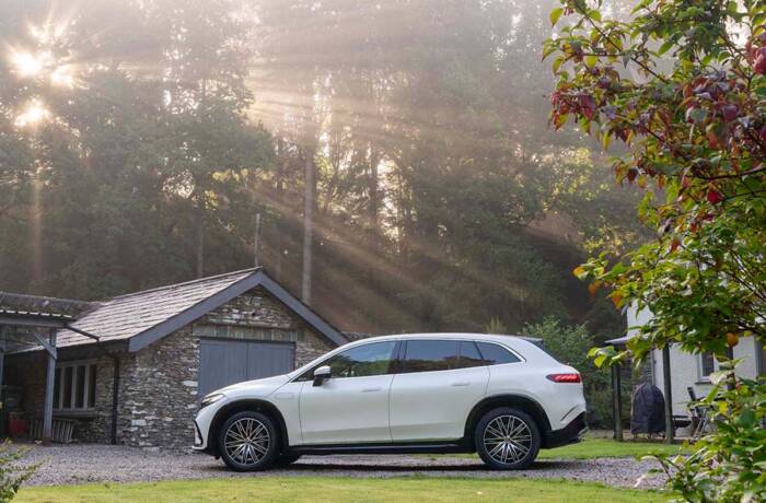 A white car by a shed in a forest