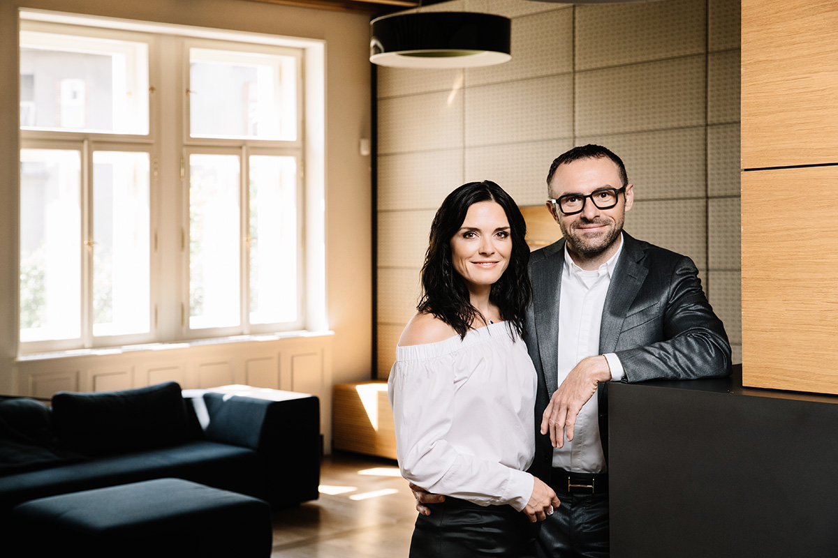 man and woman standing next to each other in a living space