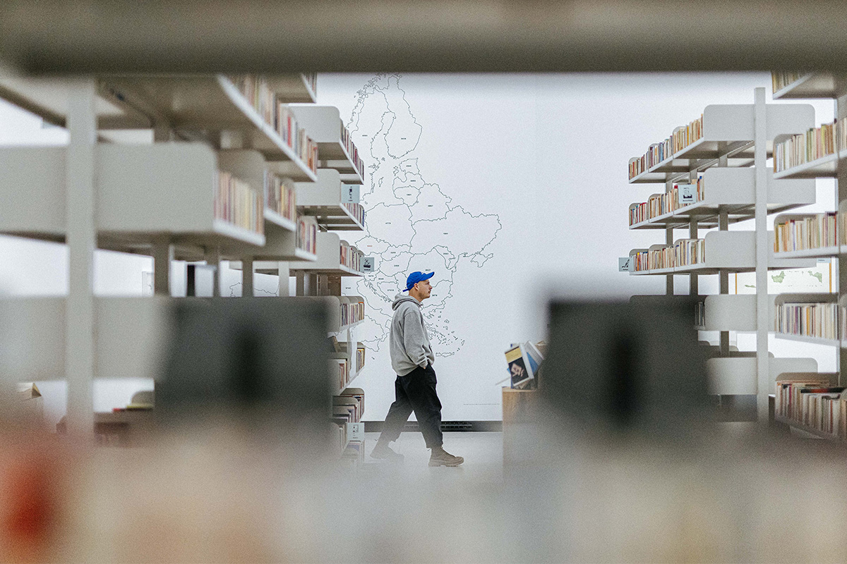 Man walking between bookshelves 