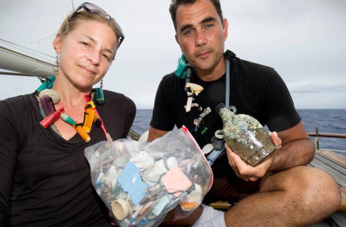 Man and woman holding rubbish from ocean