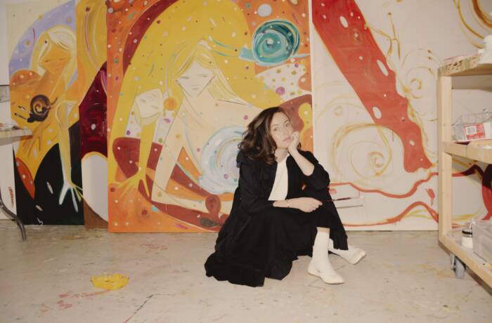 Woman sitting on the ground in front of colourful painting