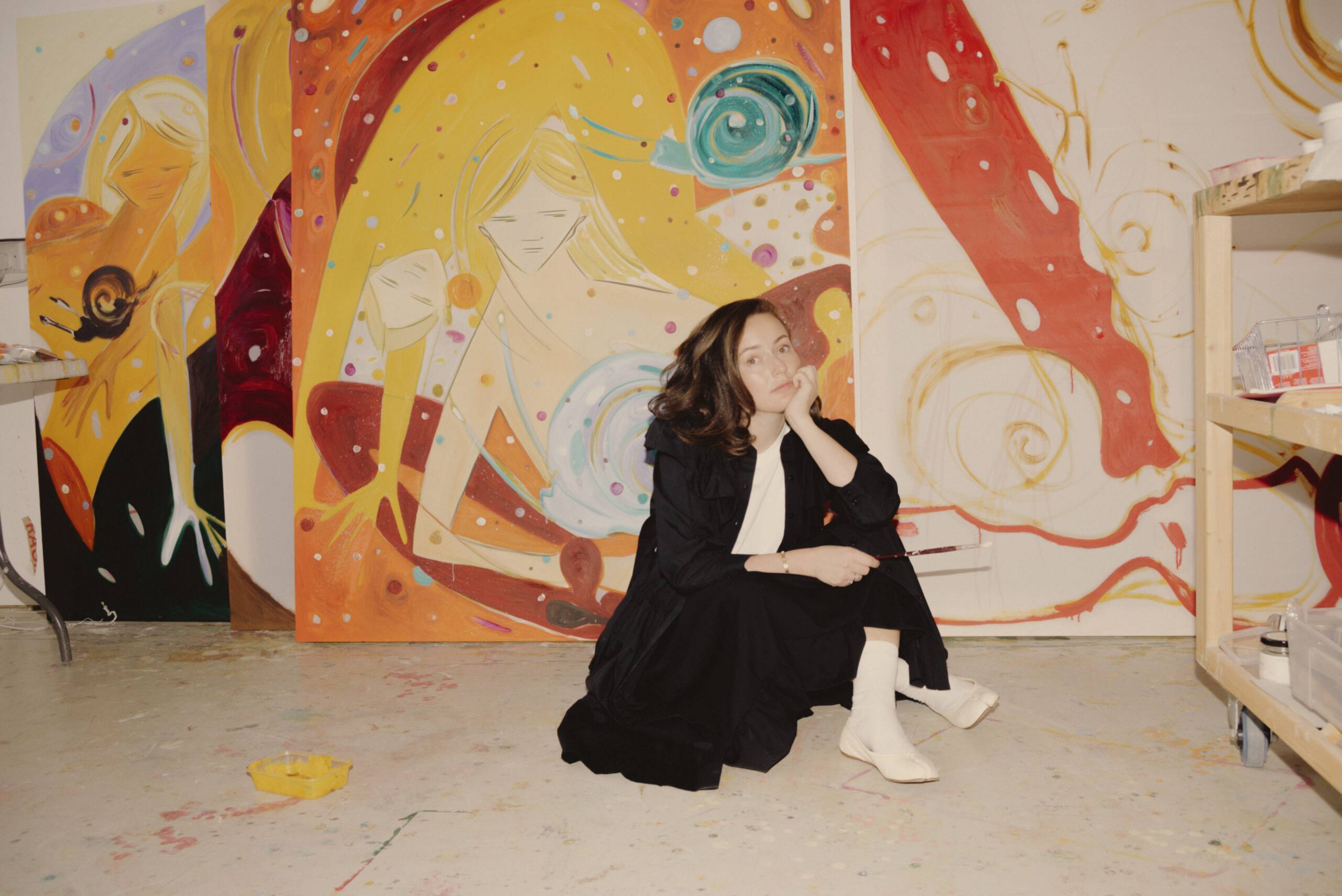 Woman sitting on the ground in front of colourful painting
